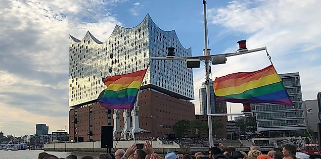 Regenbogenflaggen und Menschenmenge vor der Elbphilharmonie bei CSD-Event auf der Elbe in Hamburg