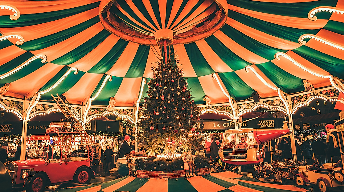 Festively decorated vintage carousel with Christmas tree under striped tent at night in Hamburg