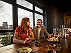 Ein Pärchen sitzt mit einem Glas Wein am Tisch des Restaurants 100/200