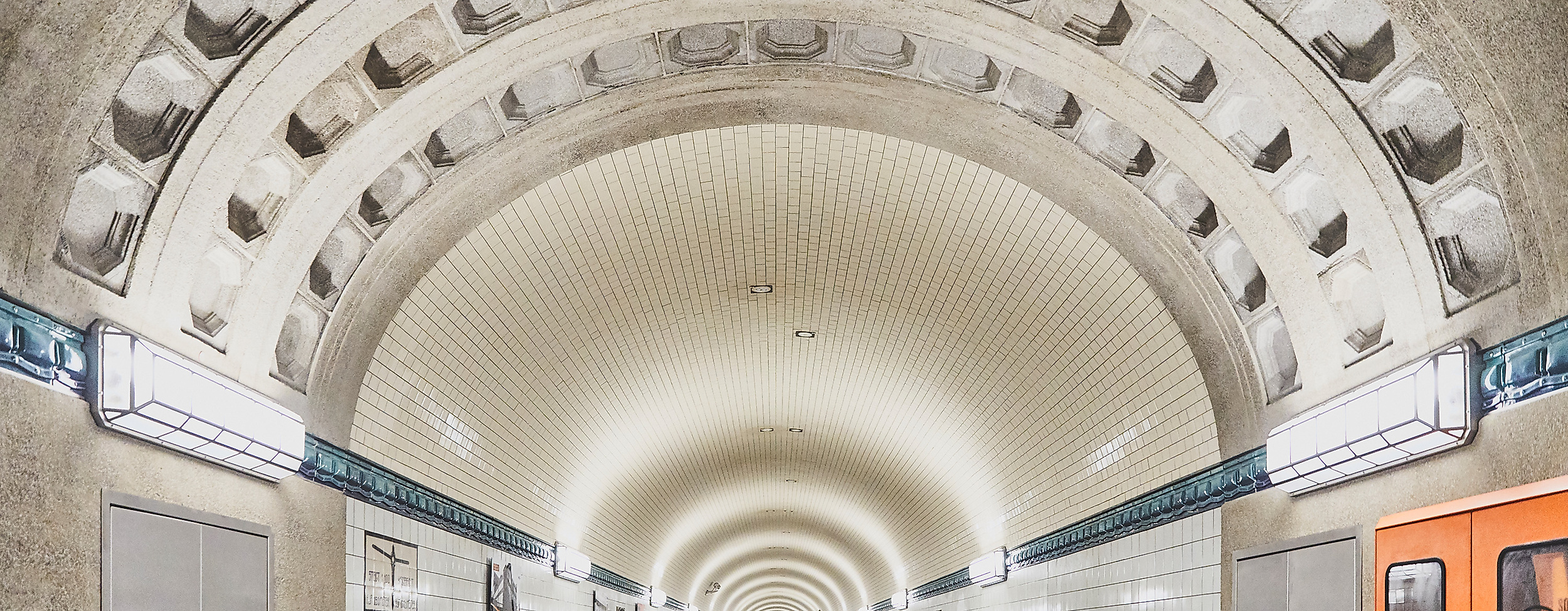 Modern sanierte Röhre des Alten Elbtunnels mit orangem Fahrzeug und gekacheltem Tunnelgewölbe