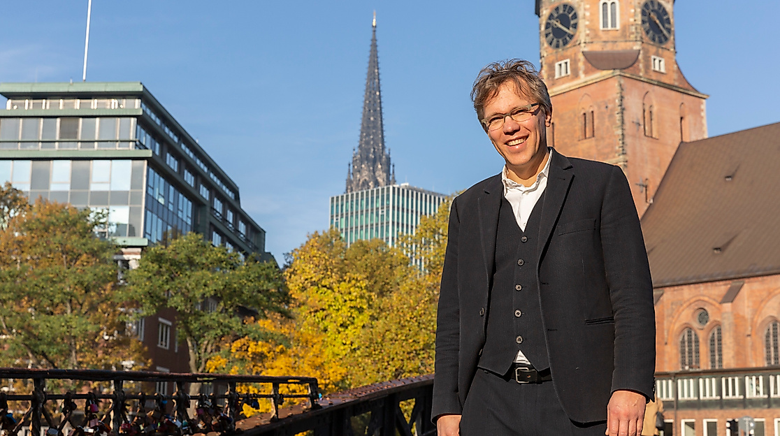 Pastor Frank Engelbrecht auf Brücke in Hamburg mit Blick auf Hauptkirche St. Katharinen und moderne Architektur