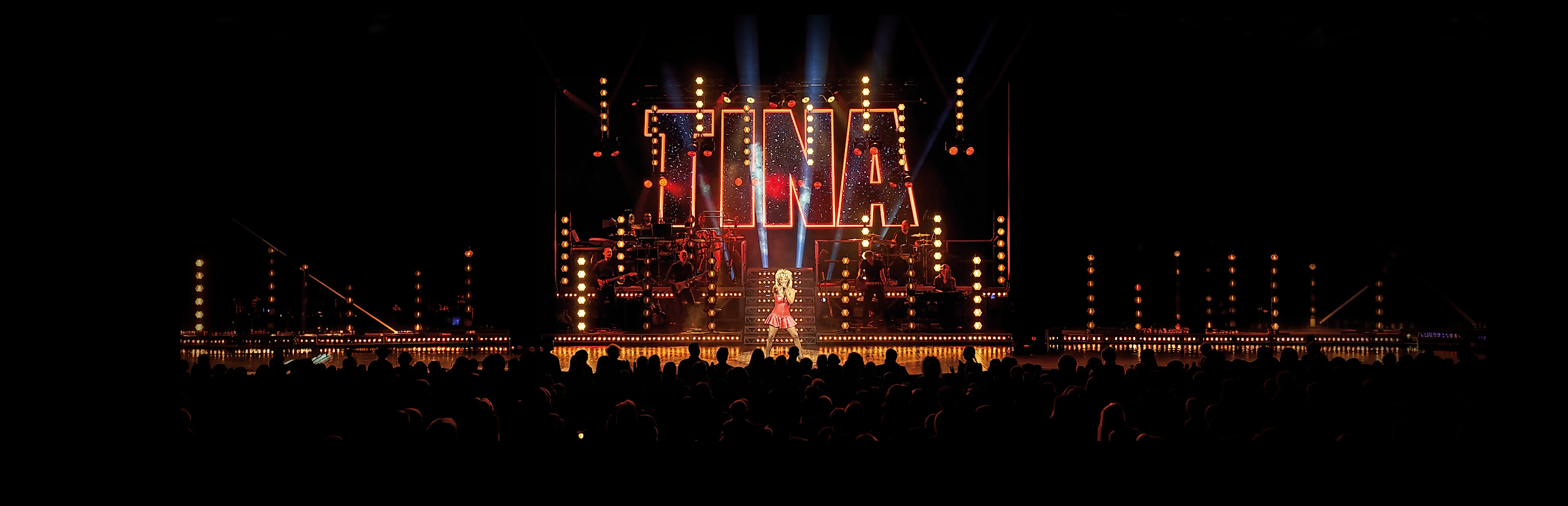 Tina Turner performt auf einer Musical Bühne mit Menschen im Publikum