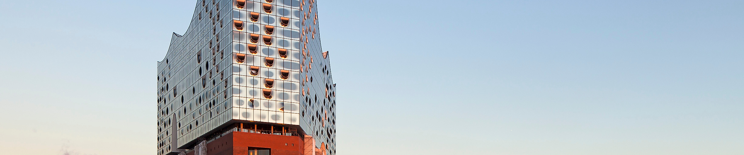 Elbphilharmonie vom Wasser aus bei Sonnenaufgang mit Blick auf den Hafen.
