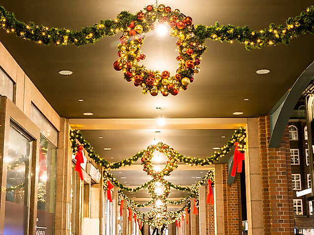 Festlich geschmückte Passage mit Lichterkränzen und Tannengirlanden in weihnachtlicher Abendstimmung