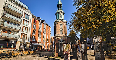 Belebter Platz an der St.-Georg-Kirche in Hamburg mit Außengastronomie, Kunstobjekten und herbstlicher Stimmung