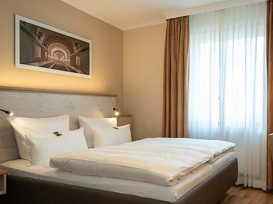 Helles, modern eingerichtetes Doppelzimmer im Hotel Rosengarten Hamburg mit großem Bett, weißer Bettwäsche und Tageslicht durch bodenlanges Fenster