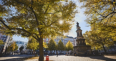 Hansaplatz in Hamburg-St. Georg mit St.-Georg-Brunnen, herbstlich gefärbten Bäumen und Sonnenlicht zwischen dem Laub