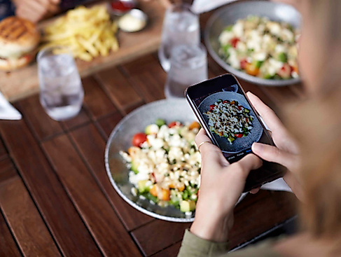 Person fotografiert Essen auf ihrem Teller