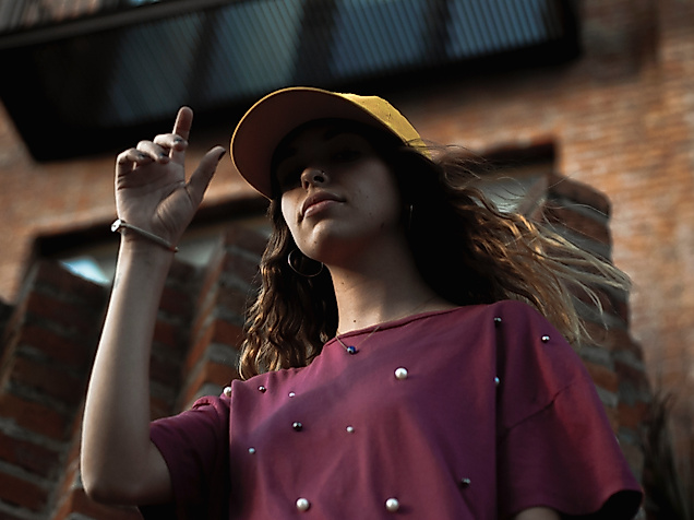 Junge Frau mit Cap und T-Shirt vor Backsteinfassade, Symbol für urbanen Streetstyle in Hamburg