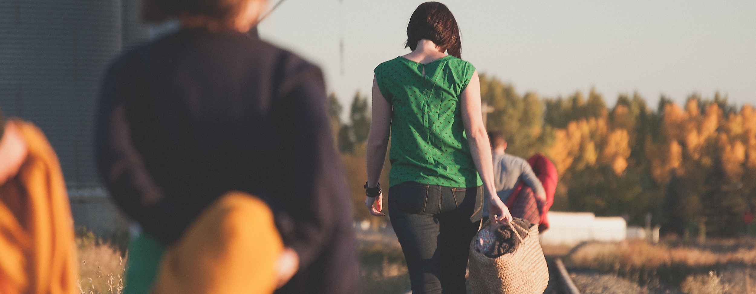 Gruppe junger Menschen spaziert bei Sonnenlicht entlang stillgelegter Bahngleise in ländlicher Umgebung