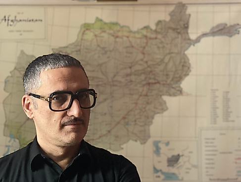 Prof. Dr. Fahim Amir steht mit ernstem Blick vor einer Landkarte