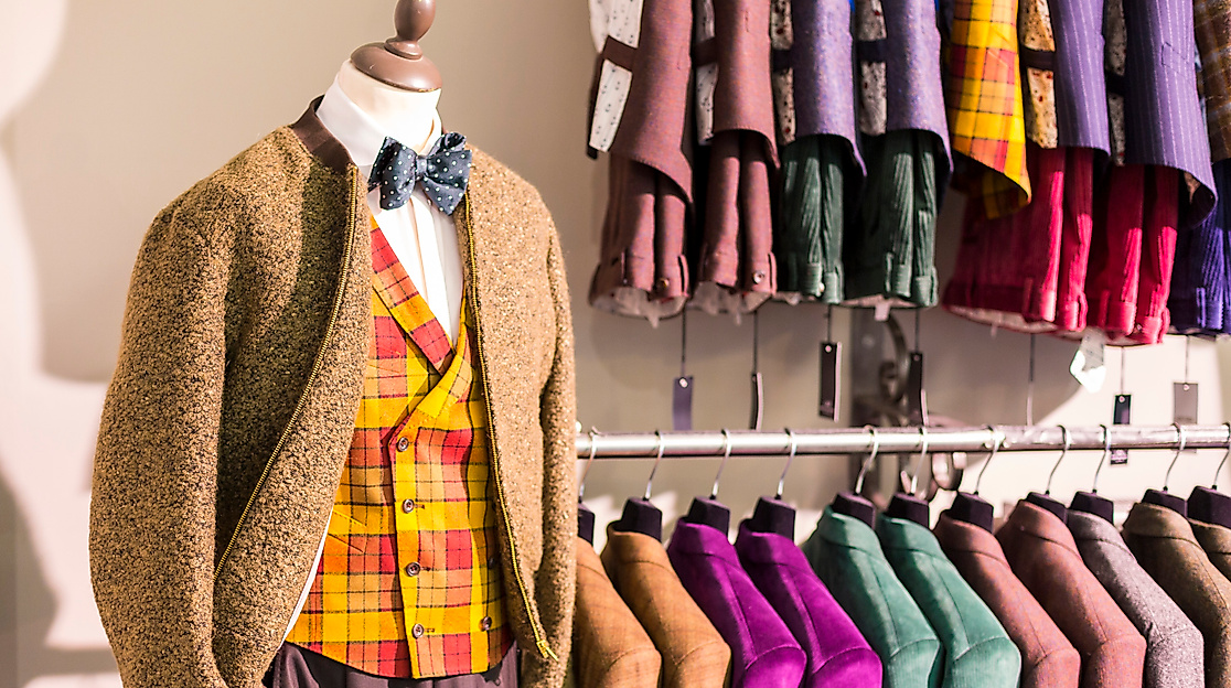 Schaufenster mit farbenfroher Herrenmode in Hamburg, darunter Weste, Sakko und Anzugjacken auf Kleiderstange