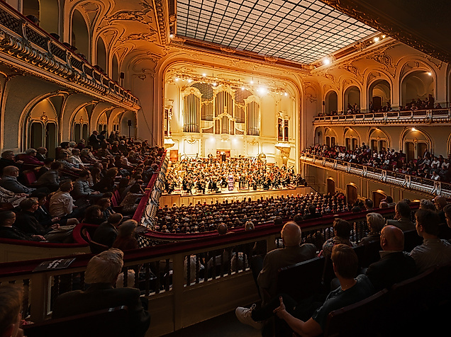 Festlich beleuchteter Opernsaal mit großem Orchester und Publikum