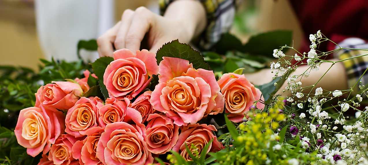 Teilnehmende arrangieren bei einem Floristik-Workshop in Hamburg einen Strauß mit Rosen und Wildblumen.