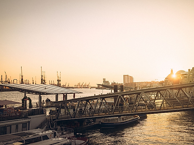 Sonnenuntergang an den Landungsbrücken mit Blick auf Elbe, Schiffe und historische Gebäude im Gegenlicht