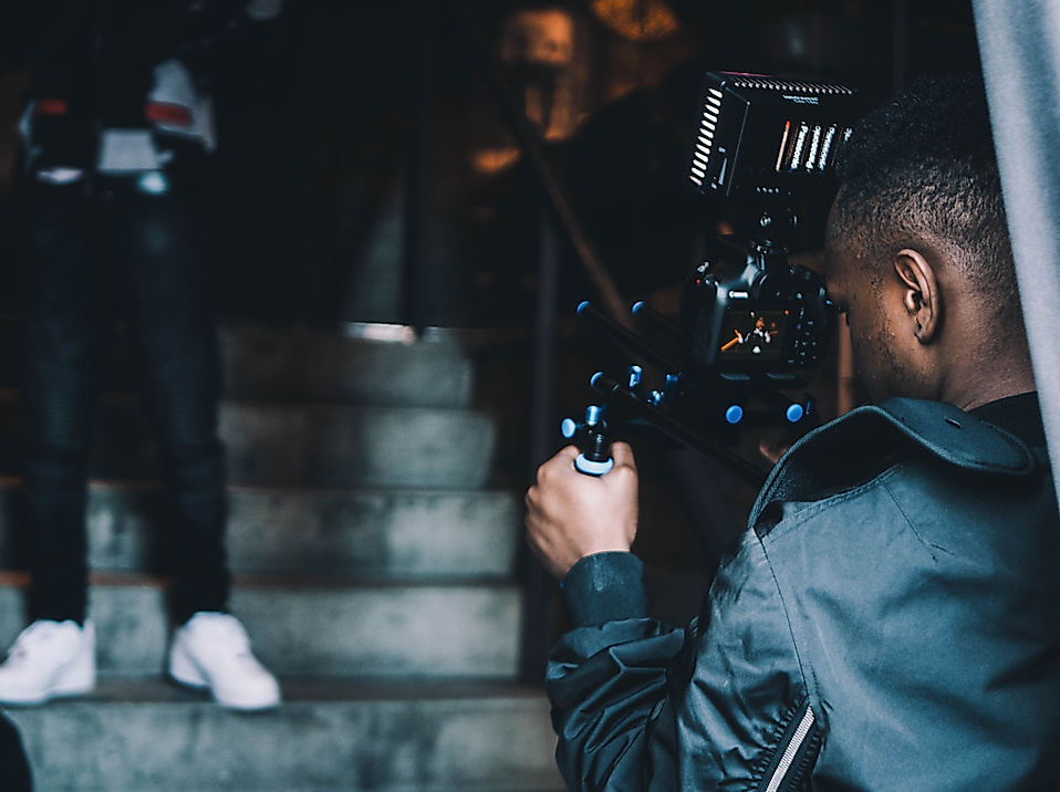 Kameramann filmt eine Person auf einer Treppe bei Innenaufnahmen in urbanem Setting