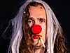 A person in a clown costume has a cigarette in their mouth. The cigarette is lit.