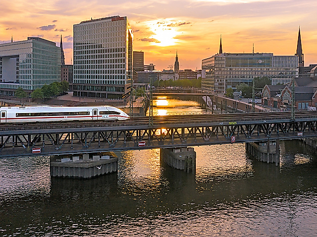 Einfahrender ICE bei Sonnenuntergang, im Hintergrund die Speicherstadt
