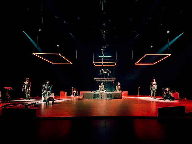Ausschnitt der Performance Eternal Dawn, die Performer*innen in roboterartigen Kostümen auf der Bühne zeigt.