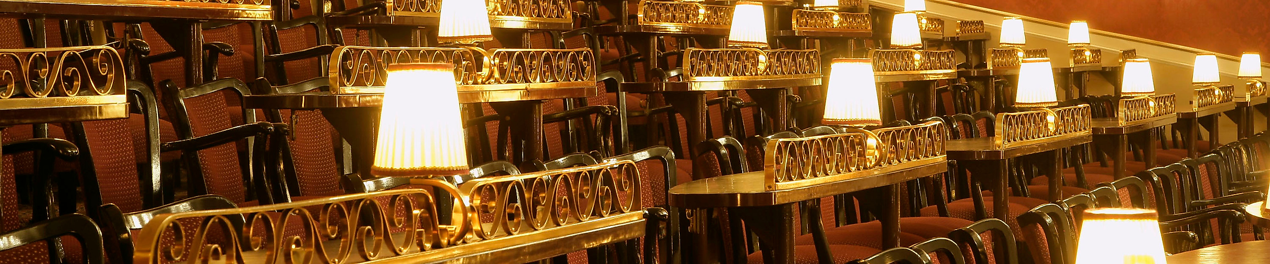 Rangbereich des Hansa-Theaters Hamburg mit roten Polstersitzen und beleuchteten Tischlampen im Varietéstil