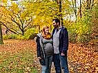 Paar im herbstlich bunten Park, eng umschlungen und lächelnd beim Spaziergang durch Laub in Hamburg