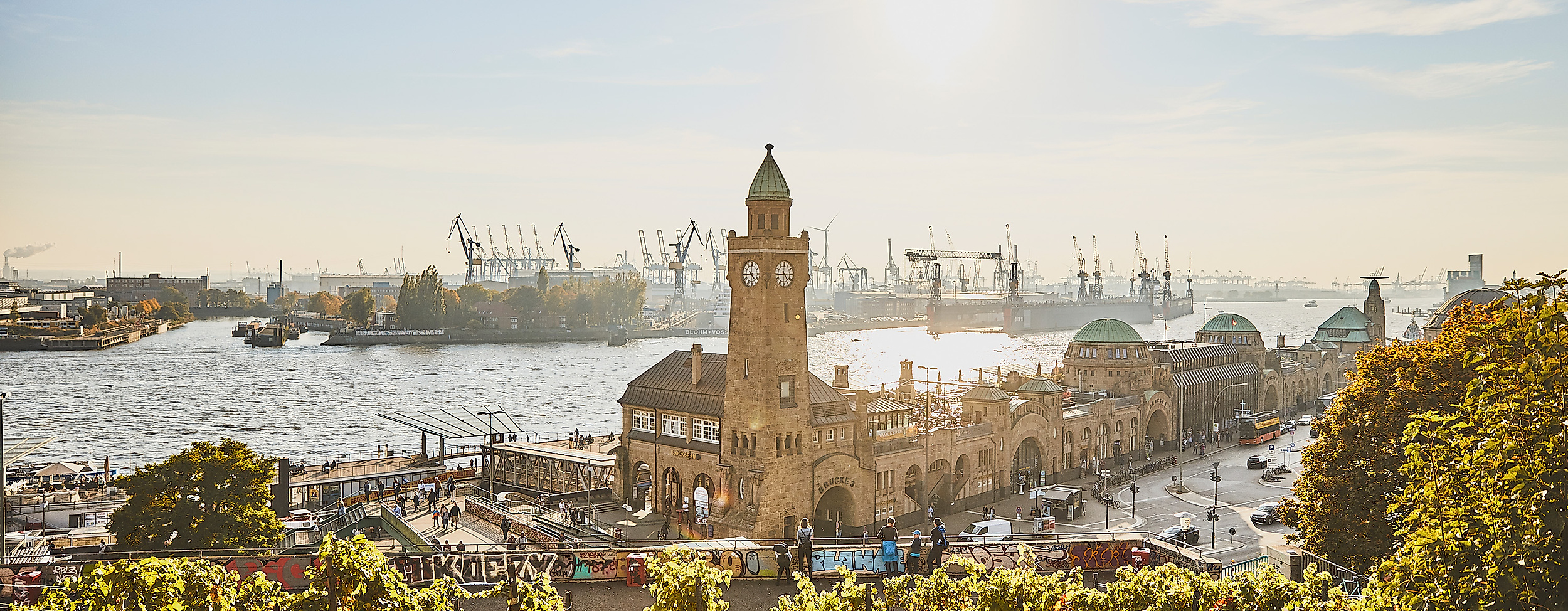 Landungsbrücken mit Uhrturm und Elbe im goldenen Licht der tief stehenden Abendsonne