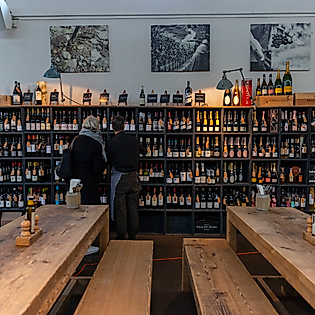 Innenraum des Vineyard Weinhandels in Hamburg Eimsbüttel mit Weinregalen, langen Holztischen und stöbernden Kund:innen