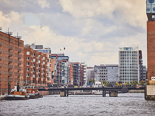 Backsteinfassaden und moderne Gebäude am Fleet in der HafenCity Hamburg mit Brücke im Vordergrund