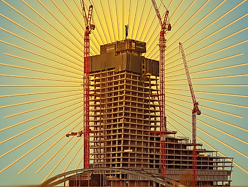 Eine Grafik einer Bauruine: Der Hamburger Elbtower steht, umzingelt von Kränen, vor einer Brücke. Er wird von gold-gelben Strahlen umrahmt.