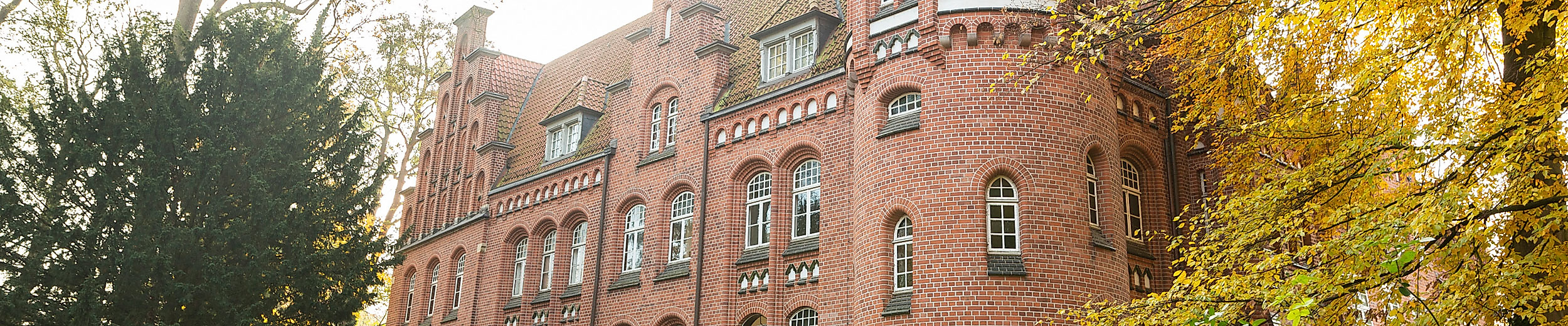 Backsteinfassade des Bergedorfer Schlosses in Hamburg, eingerahmt von herbstlich gefärbten Bäumen