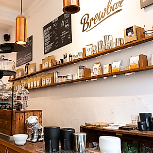 Heller Innenraum eines Hamburger Cafés mit minimalistischer Einrichtung, Kaffeebar und Produkten auf Holzregalen