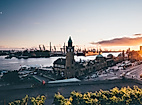 Sonnenuntergang über den Landungsbrücken mit Blick auf Uhrturm, Elbe und Hafenkräne im Hintergrund
