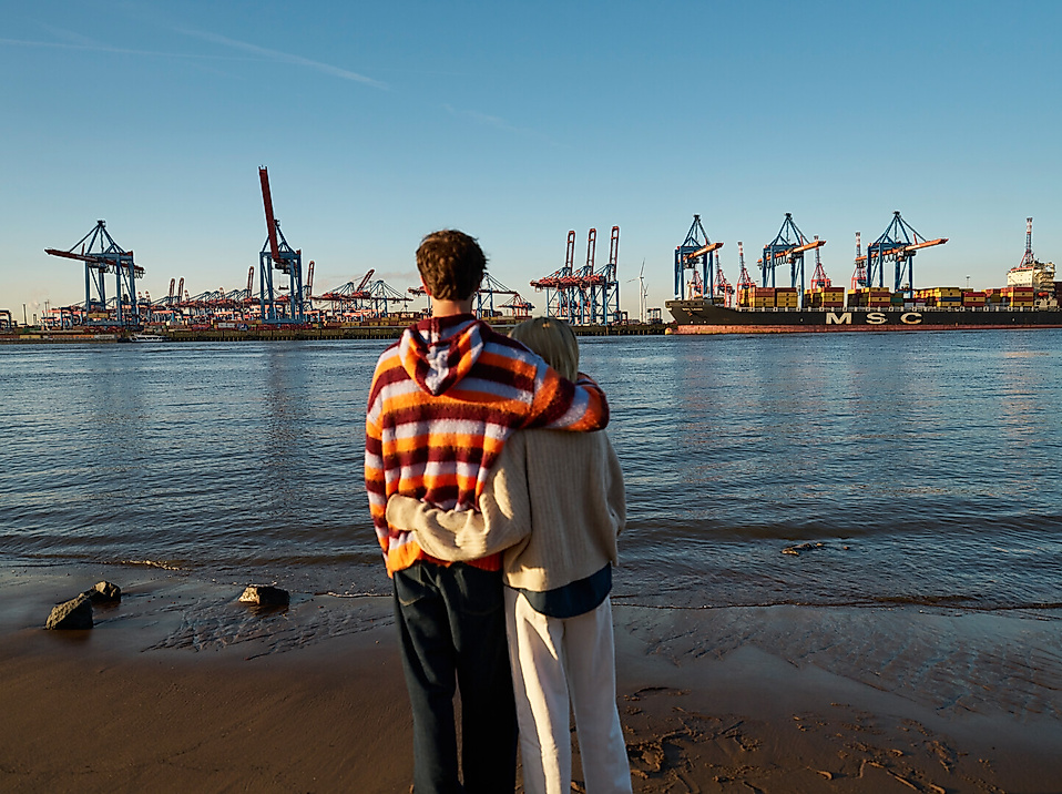 Pärchen am Elbstrand mit Blick auf Hafenkräne