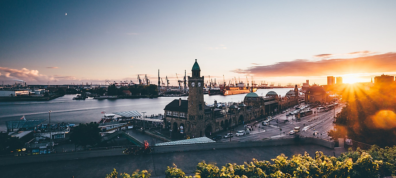 Sonnenuntergang über den Landungsbrücken mit Blick auf Uhrturm, Elbe und Hafenkräne im Hintergrund