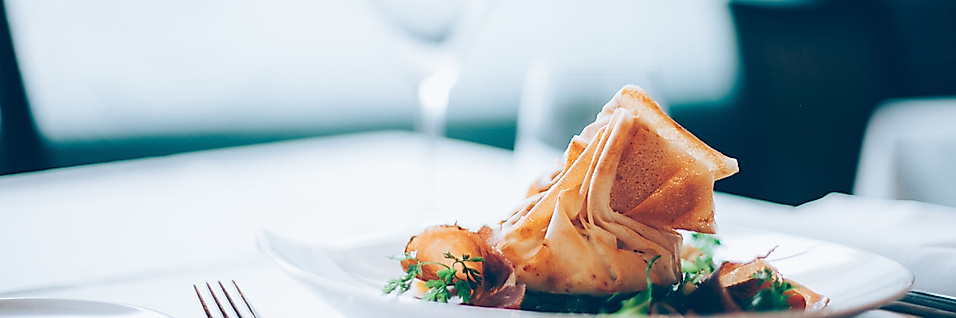 Gedämpfte asiatische Teigtaschen in Bambuskörbchen, serviert mit Dip und Stäbchen auf dunklem Untergrund