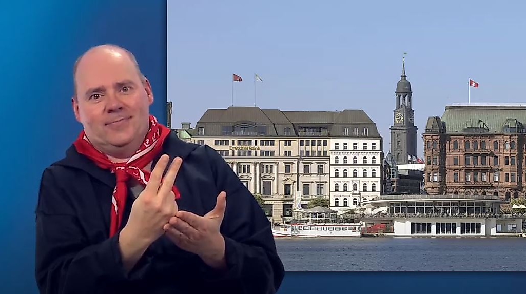 Mann gebärdet vor Panorama der Hamburger Innenstadt mit Alsterarkaden und Michel – barrierefreie Stadtinformationen.