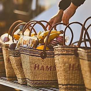 Geflochtene Obstkörbe mit frischen Früchten auf dem Hamburger Fischmarkt, Hand greift nach einem Korb