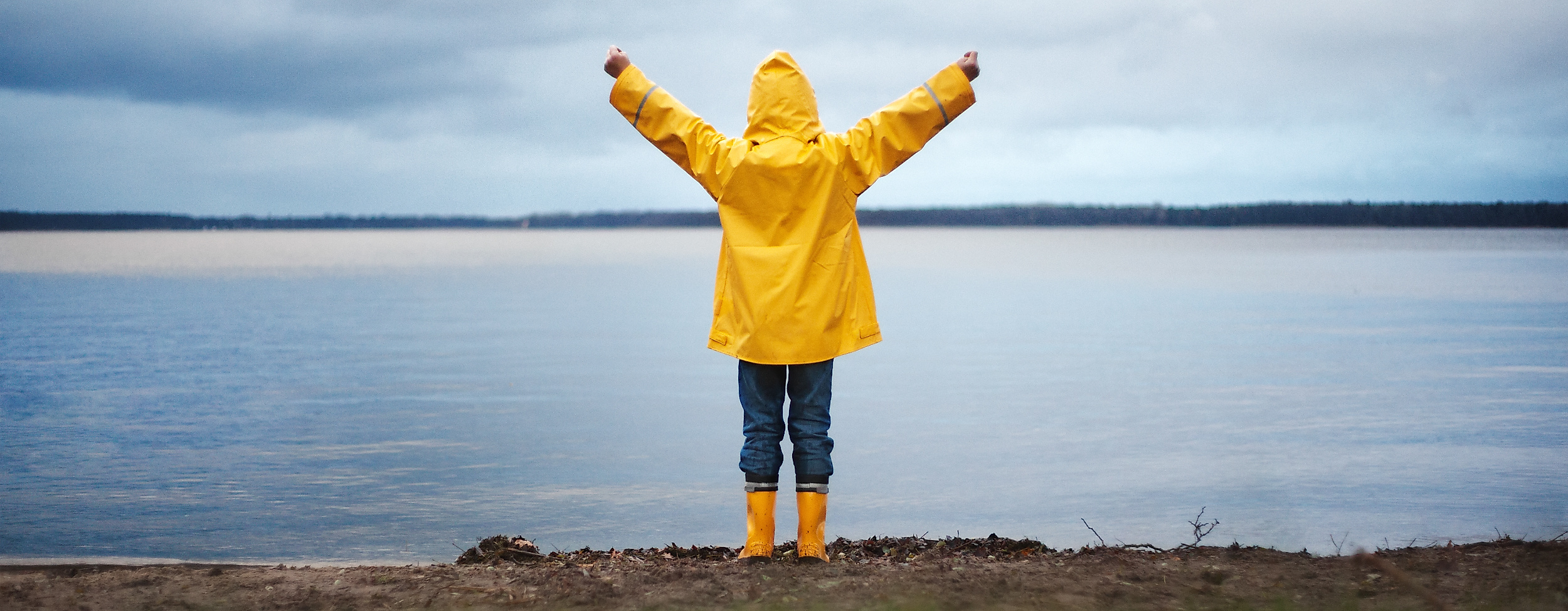 Kind im gelben Regenmantel an der Küste