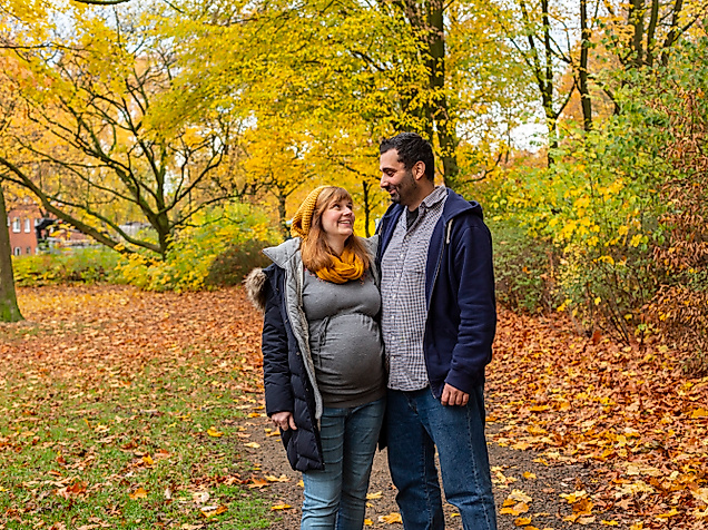 Paar im herbstlich bunten Park, eng umschlungen und lächelnd beim Spaziergang durch Laub in Hamburg