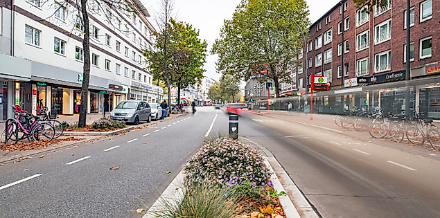 Osterstraße in Hamburg-Eimsbüttel mit Radweg, Herbstbäumen und Geschäften auf beiden Seiten