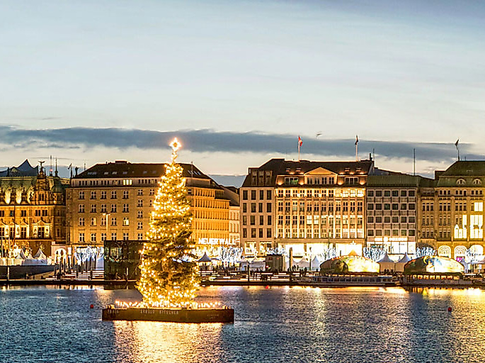 Blick von der Binnenalster auf den weihnachtlich erleuchtenen Jungfernstieg mit leuchtender Alstertanne