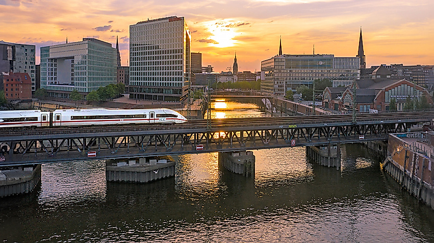 Einfahrender ICE bei Sonnenuntergang, im Hintergrund die Speicherstadt