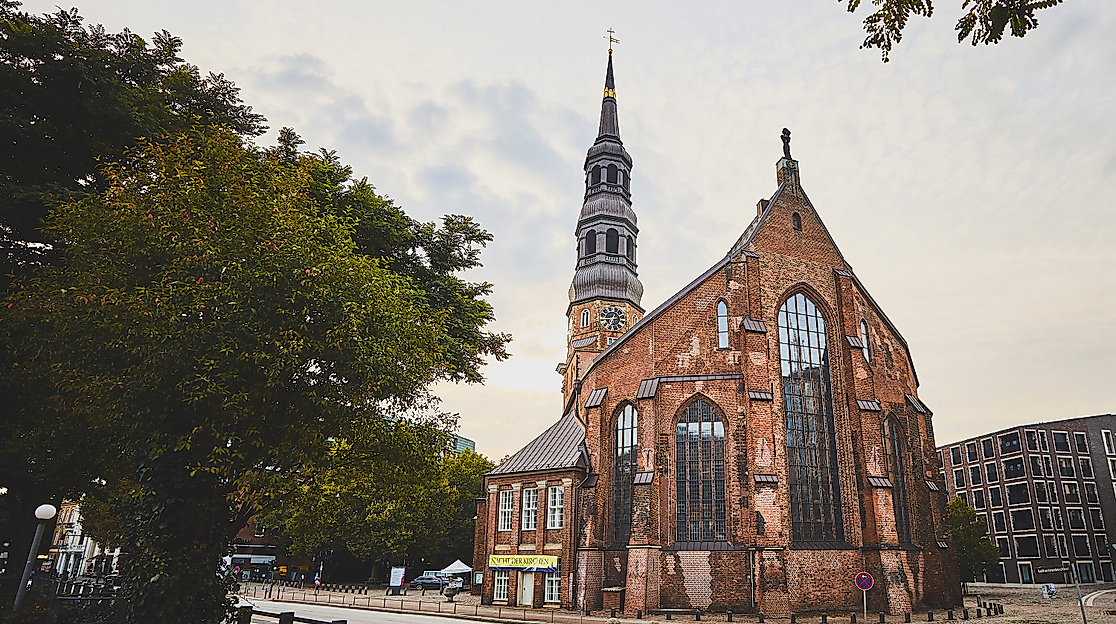 Backsteinkirche St. Katharinen mit gotischen Fenstern und Turm, eingerahmt von Bäumen am Katharinenkirchhof