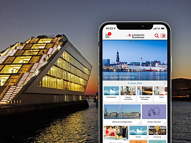 Handybildschirm zeigt Hamburg App, im Hintergrund Docks