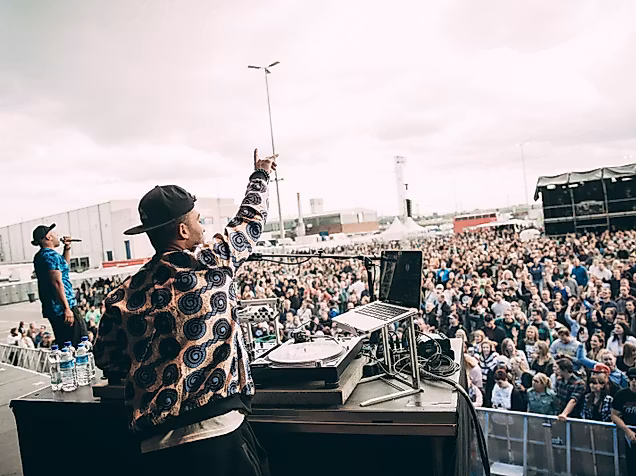 Beginner auf Festivalbühne vor tanzendem Publikum bei Open-Air-Event 