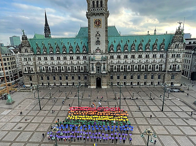 Menschen formen eine Regenbogenflagge vor dem Hamburger Rathaus – Zeichen für queere Sichtbarkeit und Vielfalt