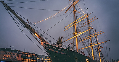 Historic sailing ship festively lit with Christmas lights at dusk in Hamburg’s harbor