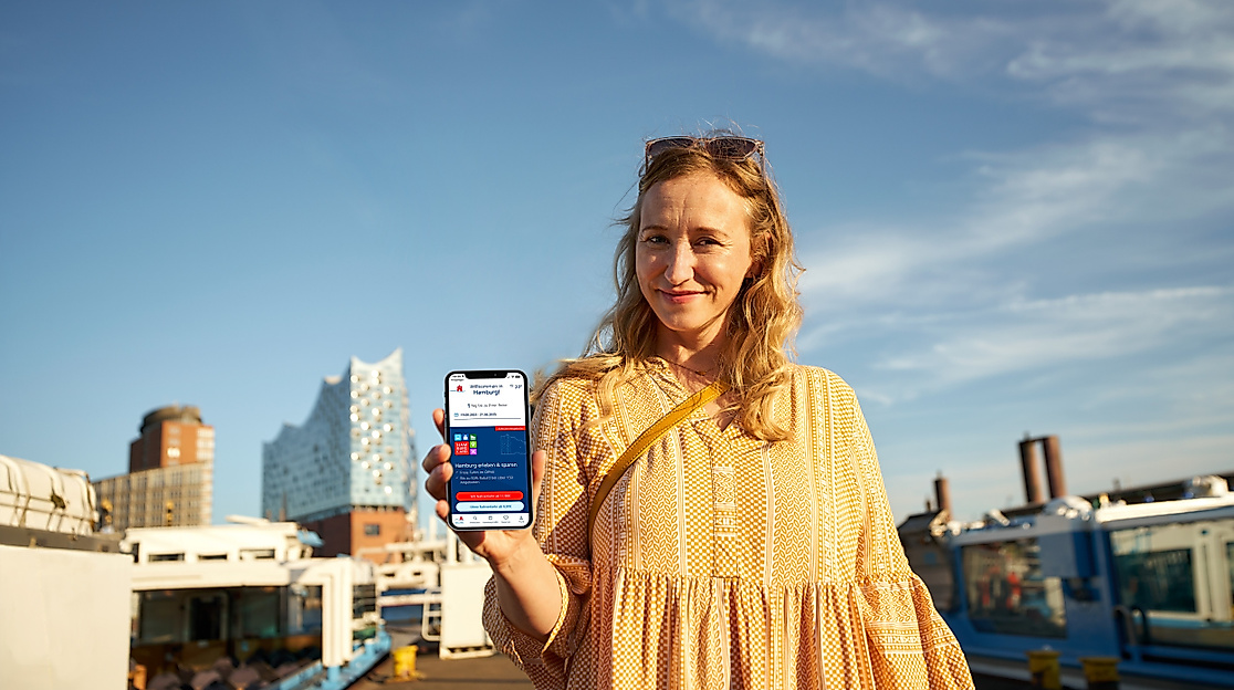 Frau mit Smartphone und Hamburg CARD App vor Elbphilharmonie