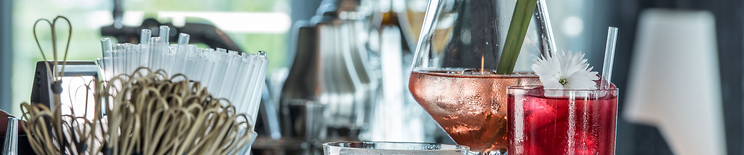 Drei stilvoll angerichtete Cocktails auf glänzender Theke in moderner Hamburger Cocktailbar