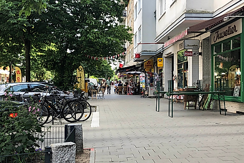 Straßenszene an der Weidenallee in Hamburg mit Cafés, kleinen Läden und abgestellten Fahrrädern im Schatten
